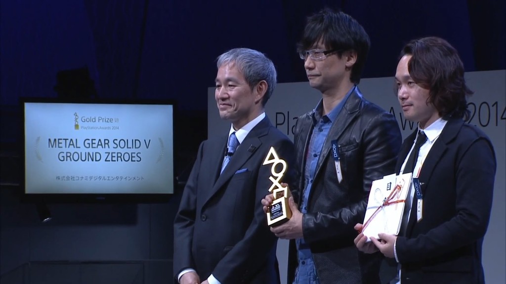 O gênio, Hideo Kojima (ao centro), recebendo o prêmio "Gold Prize" pelo MGSV: Ground Zeroes  na PlayStation Awards de 2014.